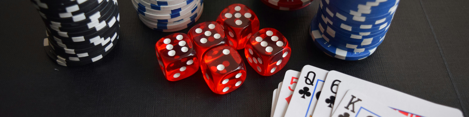 Poker chips, dice and playing cards on a black table